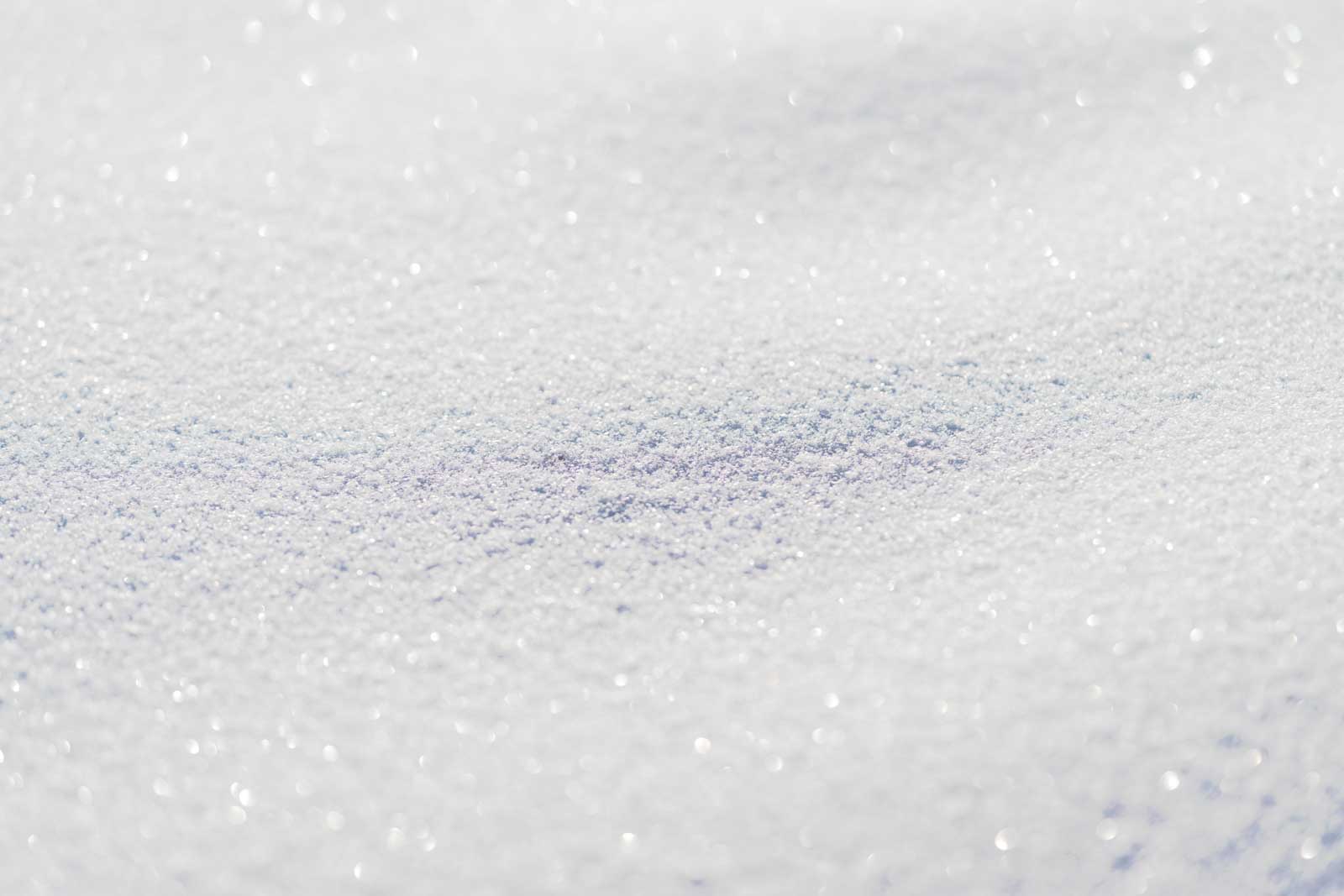 Crystalline snow grains with intense reflective gleam highcontrast macro texture, sparkling highlights for minimalist design or scientific reference, tactile visual interest